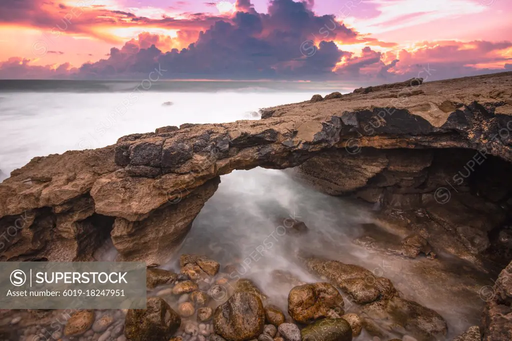 Arch shaped rock formation in the coastline at the sunset.