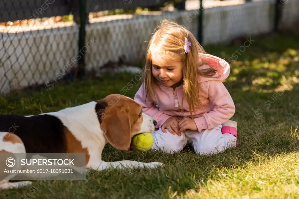 Child playing with dog on grass.