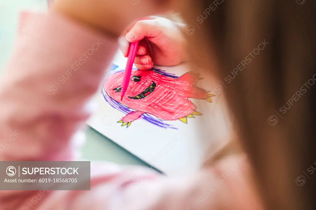 girl draws smiling pink monster with purple hair, look from under arm