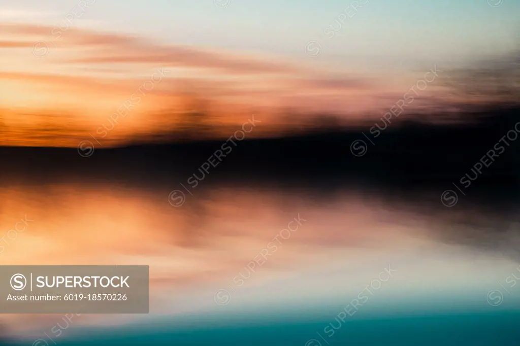 Orange and teal abstract sunset over a forest  and a lake