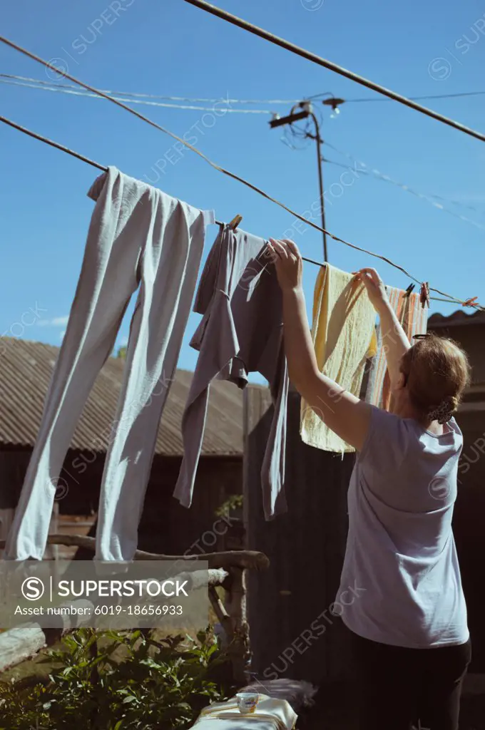 Woman dries clothes on clothesline on sunny day