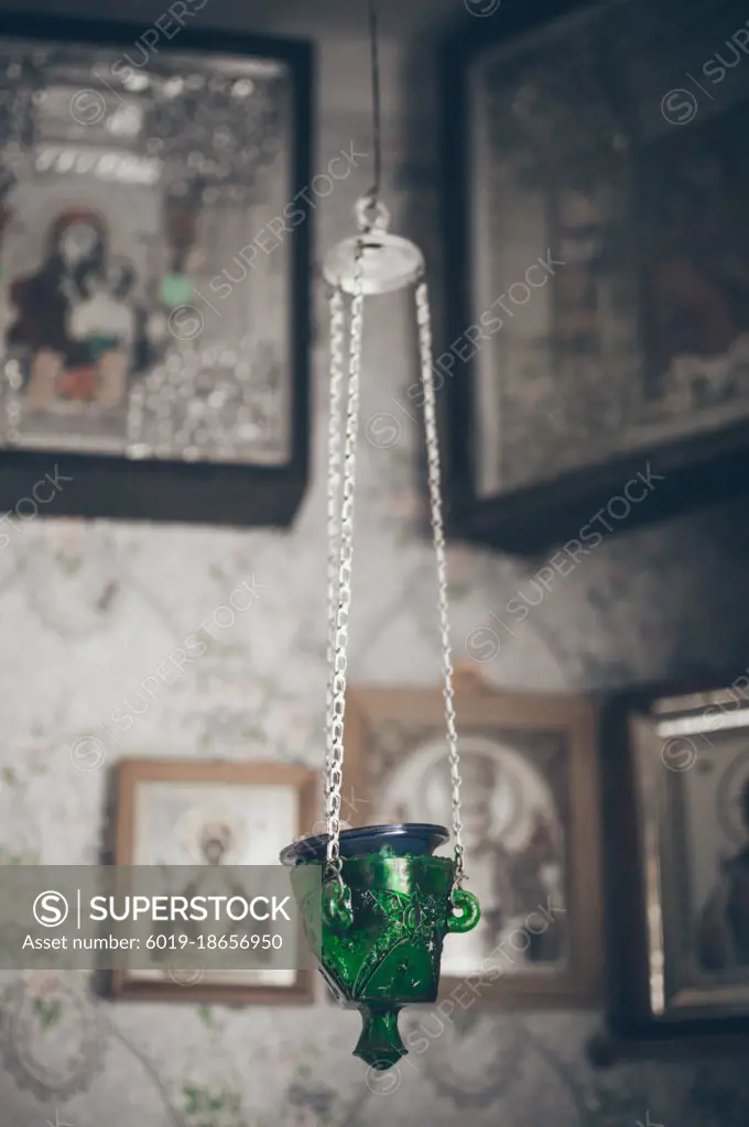 Vintage lamp on chain against blurred icons in village house