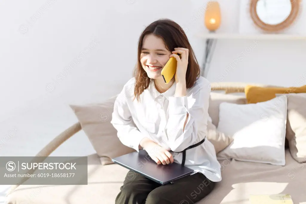 Young woman is talking on the smartphone from home office