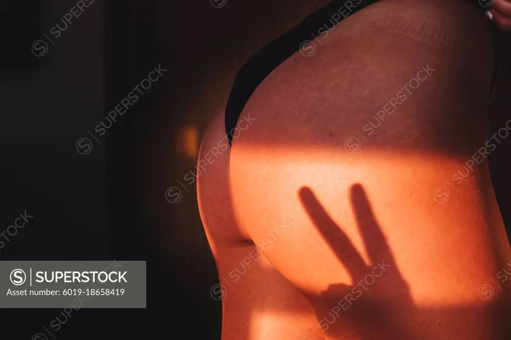 two finger shadow cast on a woman's ass