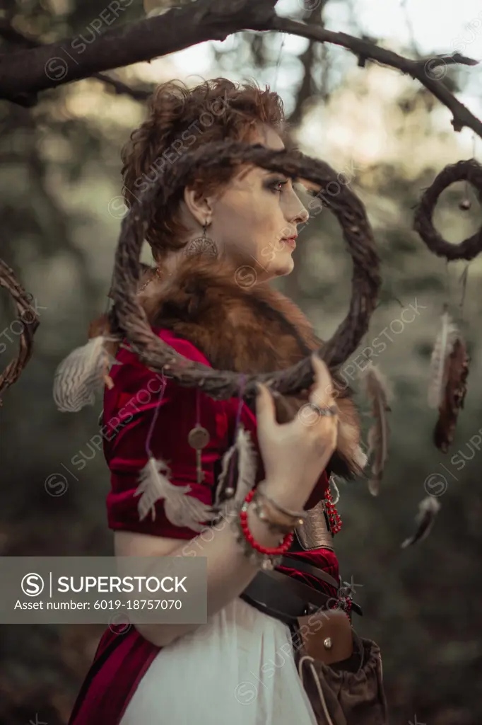 Witch with short hair in dress against the background of wild nature