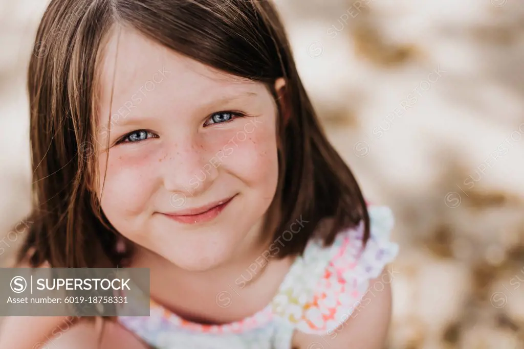 Smiling girl with bright blue eyes and freckles looks at camera