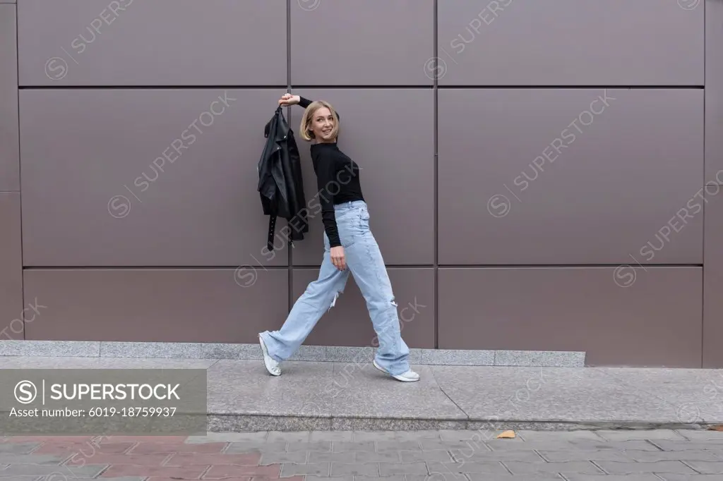 Woman walks in front of a gray wall