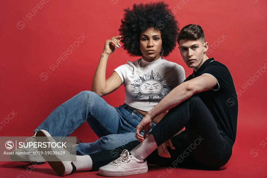 Multiracial couple studio shooting over a red background