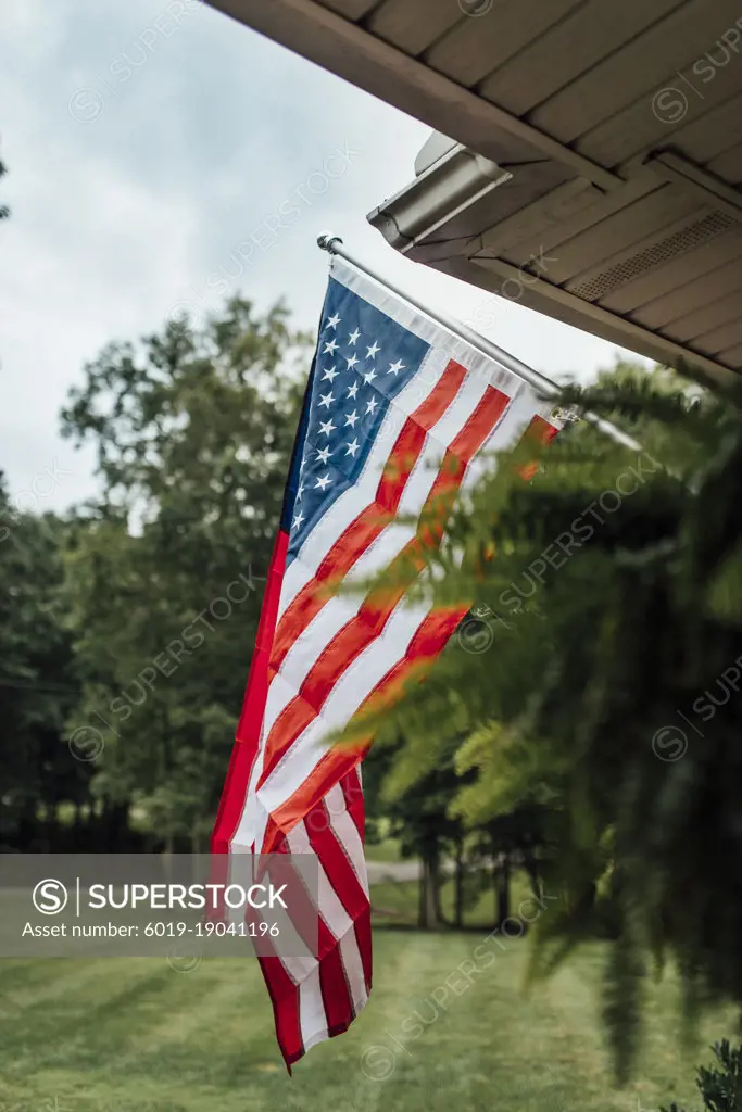 American flag on front porch with yard in background
