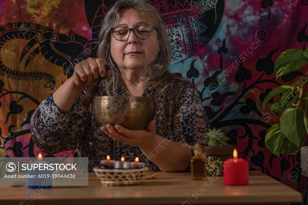 older woman ringing a Tibetan singing bowl