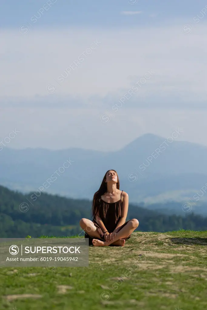 Female sitting in pose of lotus in mountains.