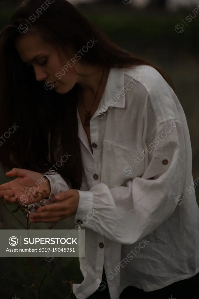 Woman embracing, touching wild plants by hands.