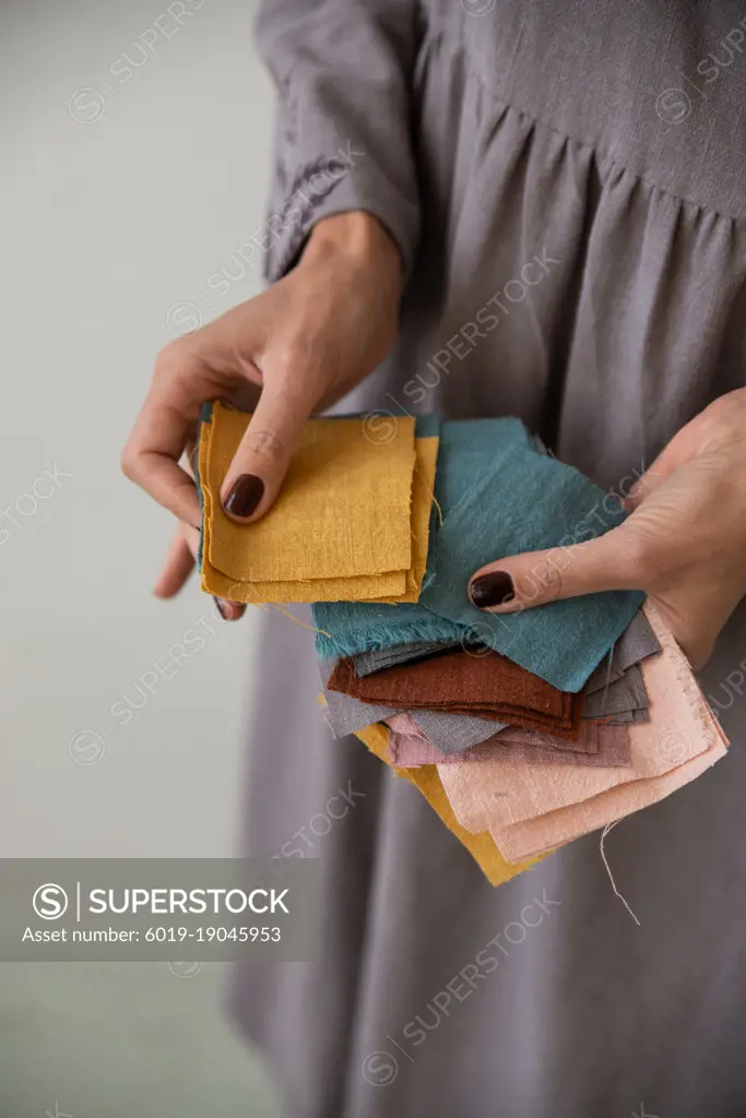 Woman wearing grey holding prices of colourful linen tissue examples