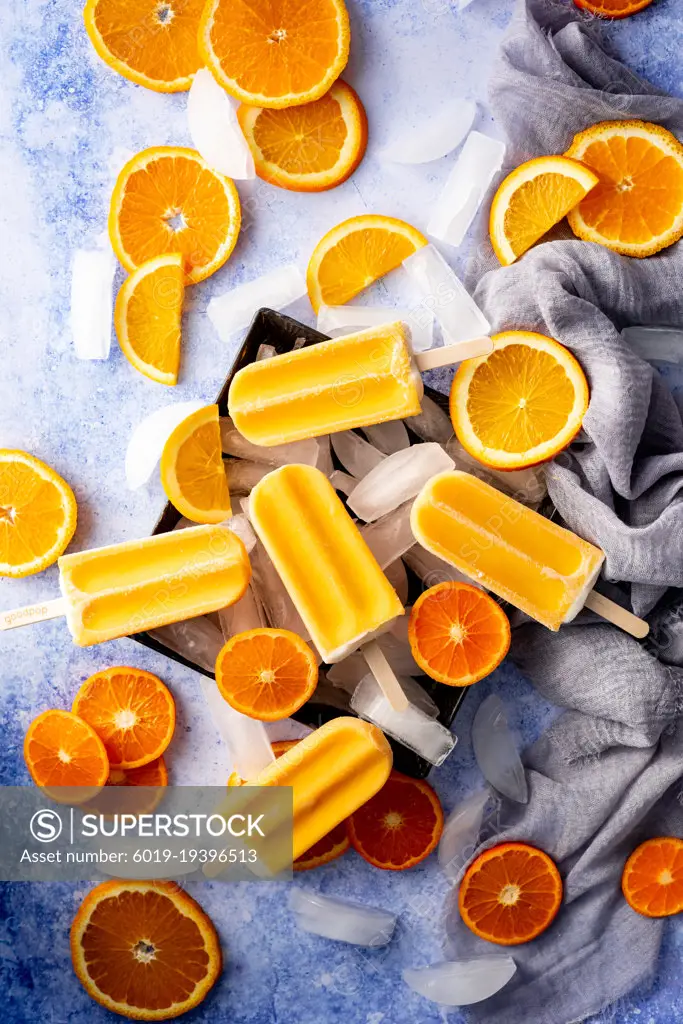 Five orange popsicles on ice