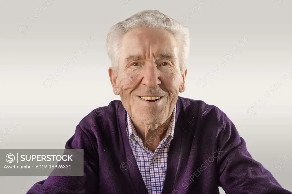 90 year old man in purple sweater looking at camera happy