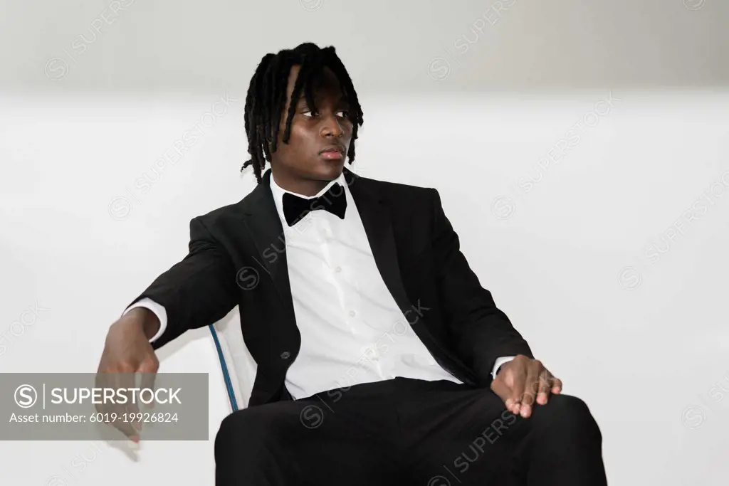 Portrait of the black man with dreadlocks wearing a suit sittin