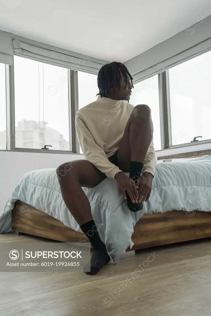 Black man with dreadlocks wearing vintage clothing sitting on th