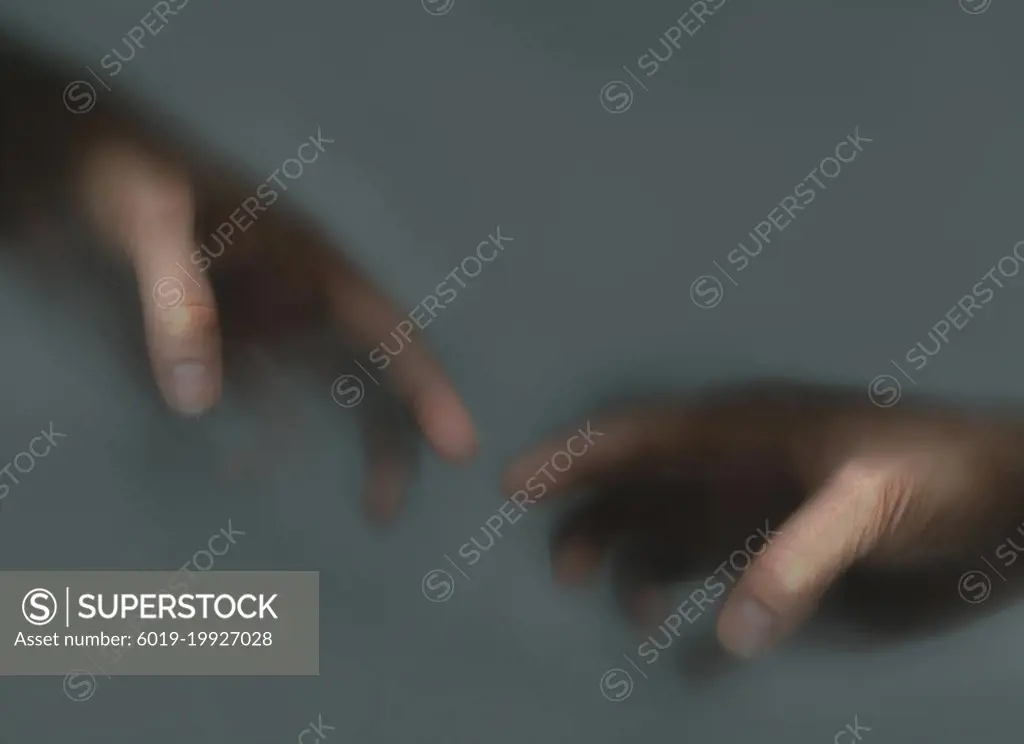 Two hands reaching out to each other in the mist
