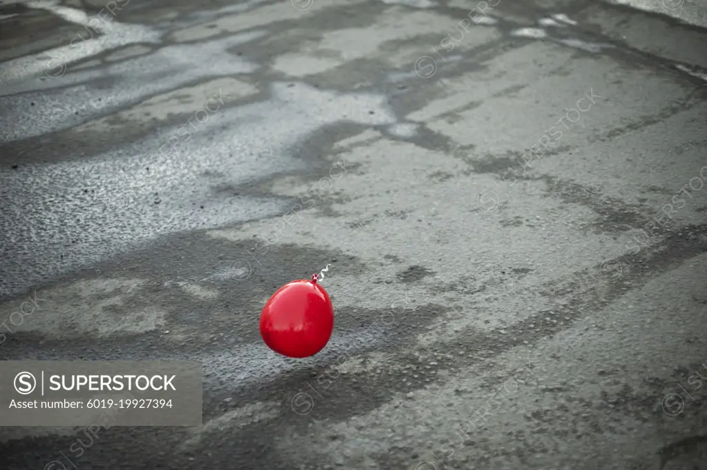 Red ball flies over asphalt. Balloon outside.