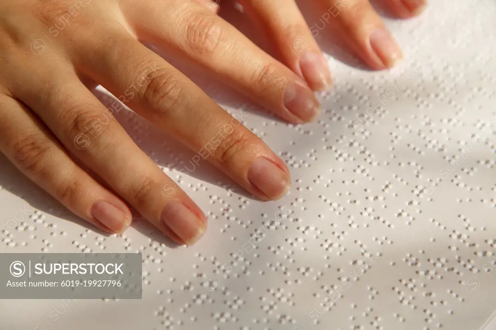 Woman's fingers on a book page with braille