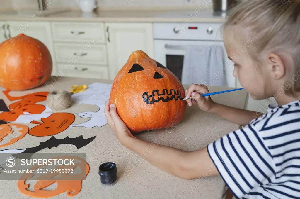 Girl decorating and painting pumpkin for Halloween.