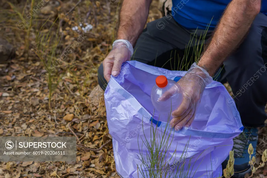 environmentalist man picking up garbage from the field