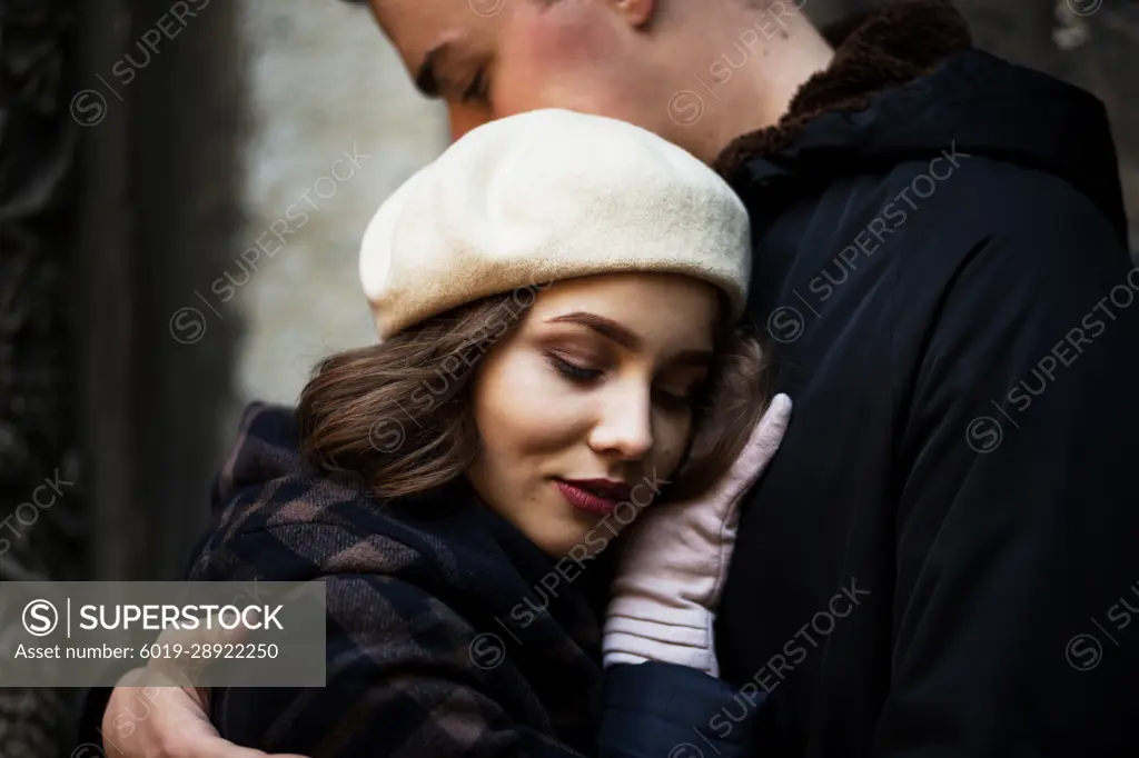 man and woman stand embracing in middle of European city in autumn