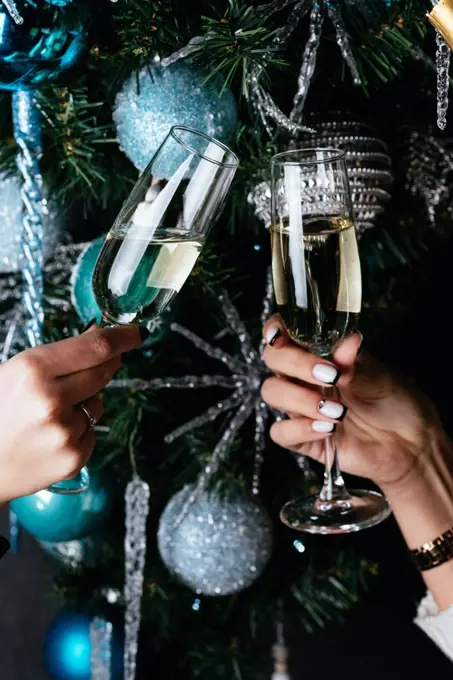 women's hands holding champagne glasses on the background of a C