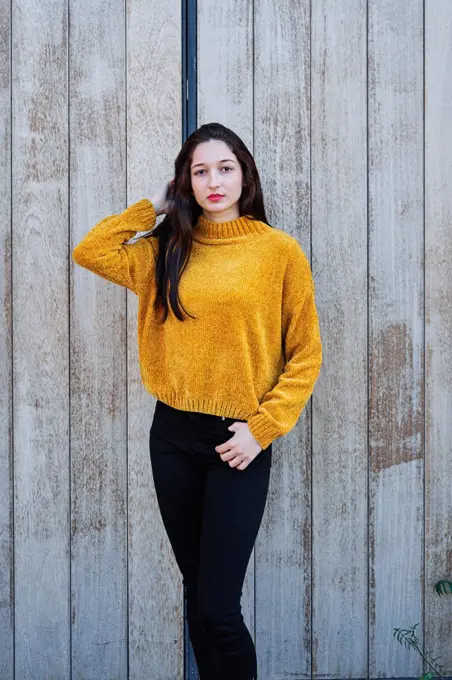 Vertical photo of a Portrait of a young brunette girl with painted lips and in a yellow sweater