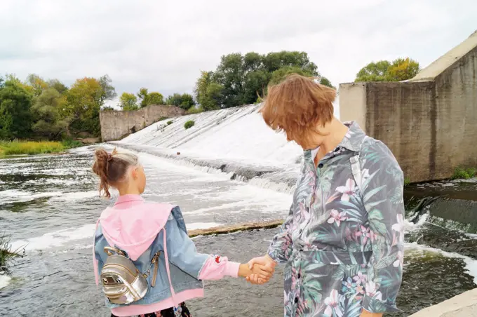Mother and daughter hold hands on the dam