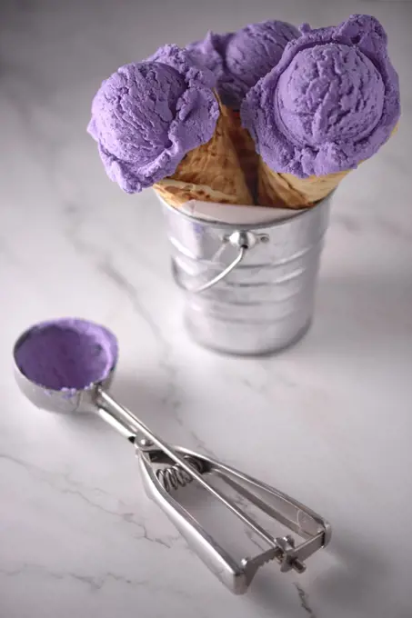 three blueberry ice creams on white marble in metal container