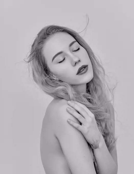 Potrait of young attractive woman with long and shiny blonde hair on white, topless. Friendly natural casual black and white portrait.