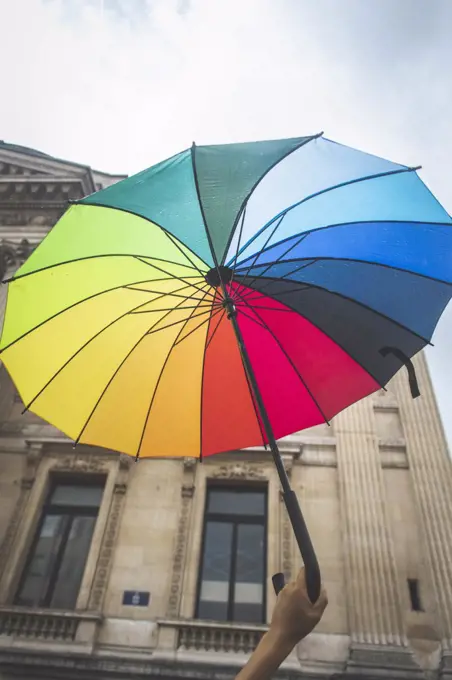 A person hold a rainbow umbrella in the air