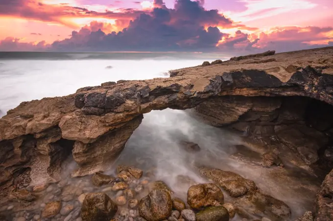 Arch shaped rock formation in the coastline at the sunset.