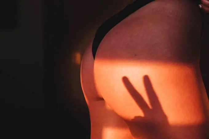 two finger shadow cast on a woman's ass