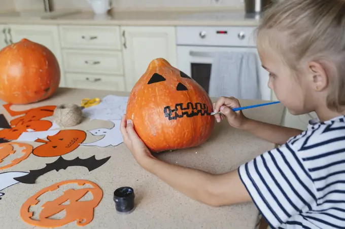 Girl decorating and painting pumpkin for Halloween.