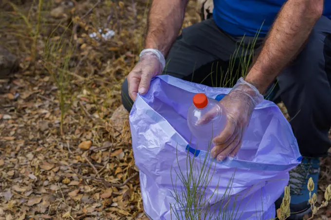 environmentalist man picking up garbage from the field