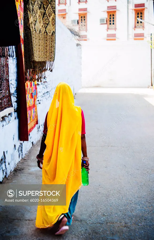 Woman walking through the city of Pushkar with a colorful yellow sari, Pushkar, India