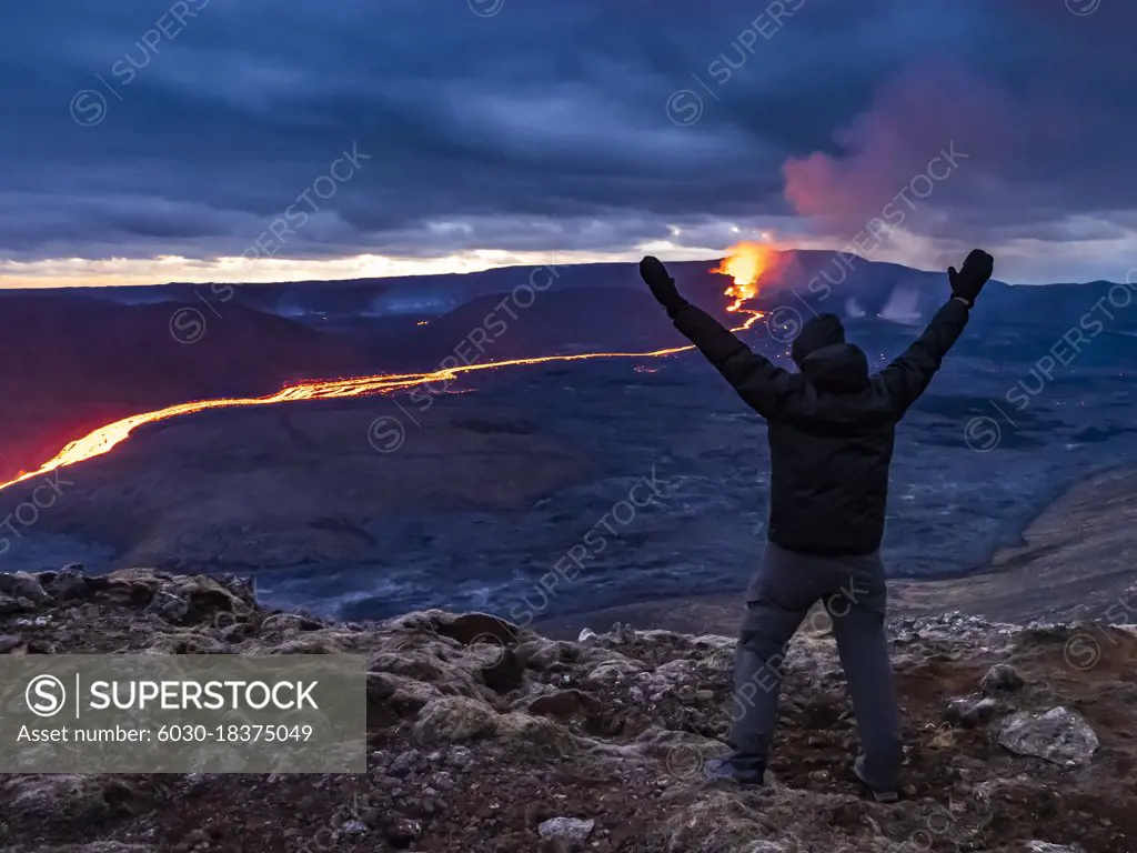 Celebration, Trekker views glowing river of magma and Fagradalsfjall Volcanic eruption at Geldingadalir, Iceland