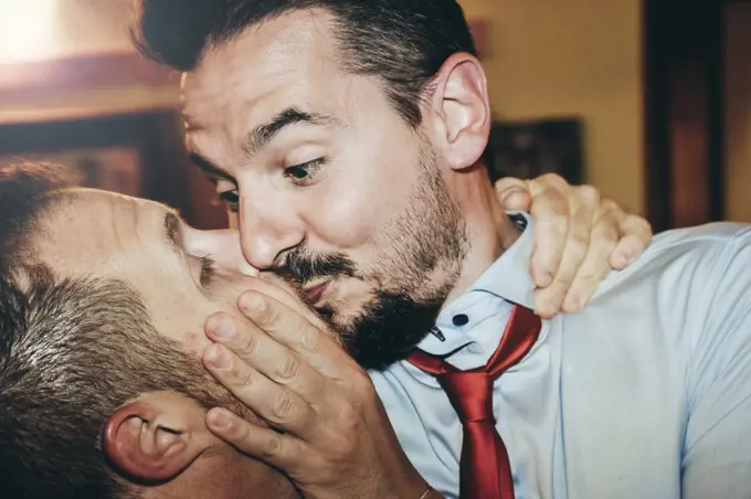 Loving gay couple kissing passionately at the wedding party - Two handsome men having romantic kiss indoors - LGBT wedding and rights concept