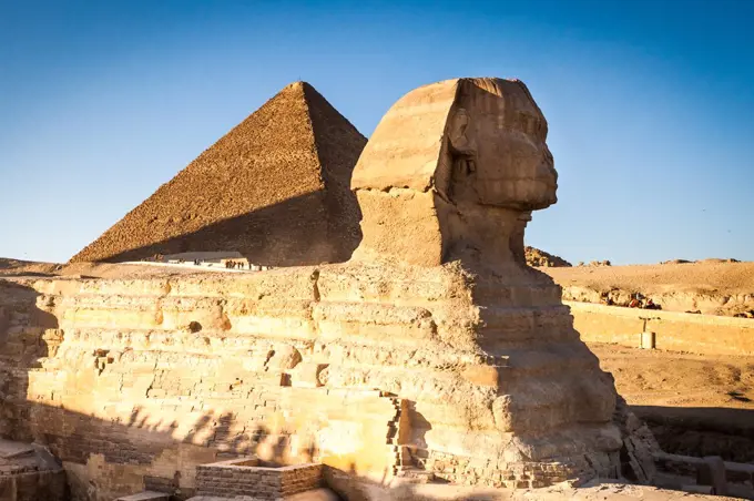 Egyptian sphinx with a ptramid in background at sunset
