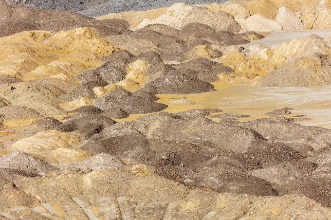 Photograph of crushed sand and stone laying on the ground in a large quarry