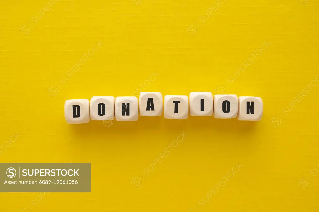 Donation word over wooden blocks, yellow background. Charity kindness concept