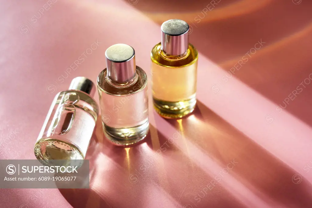 Glass bottle cosmetics with oil for beauty or skin care on pink background, natural sun light and shades, top view