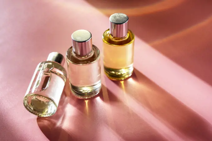 Glass bottle cosmetics with oil for beauty or skin care on pink background, natural sun light and shades, top view