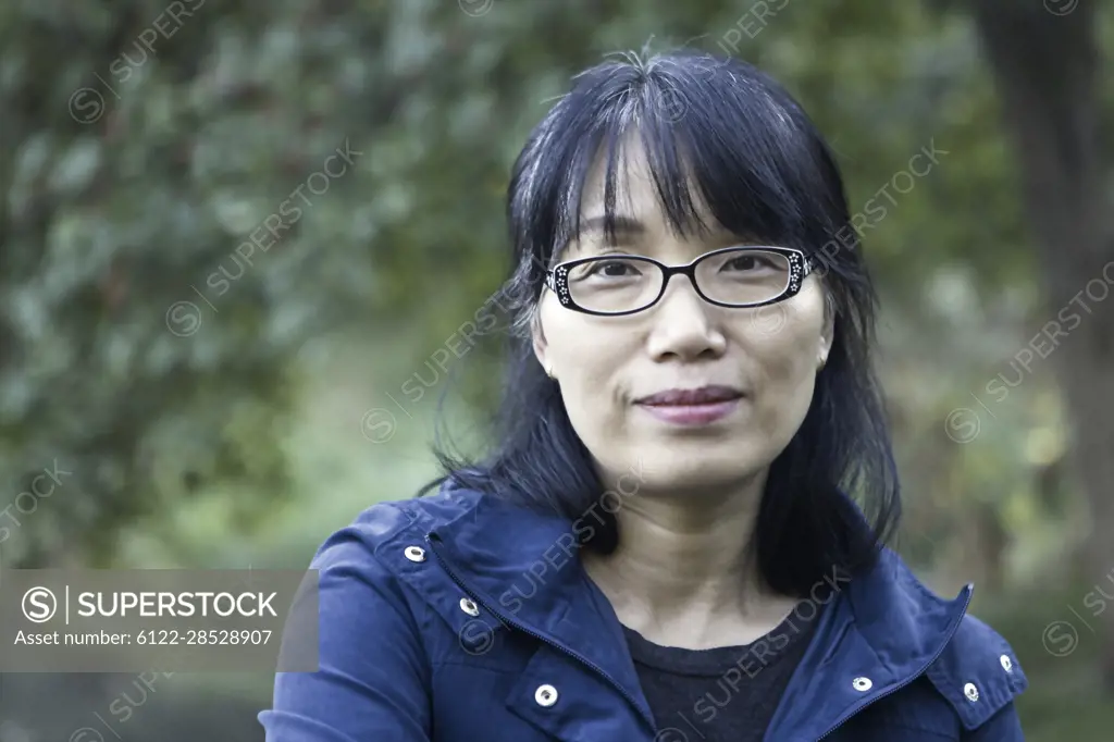 A pretty middle age Korean woman with a pleasent smile in a park