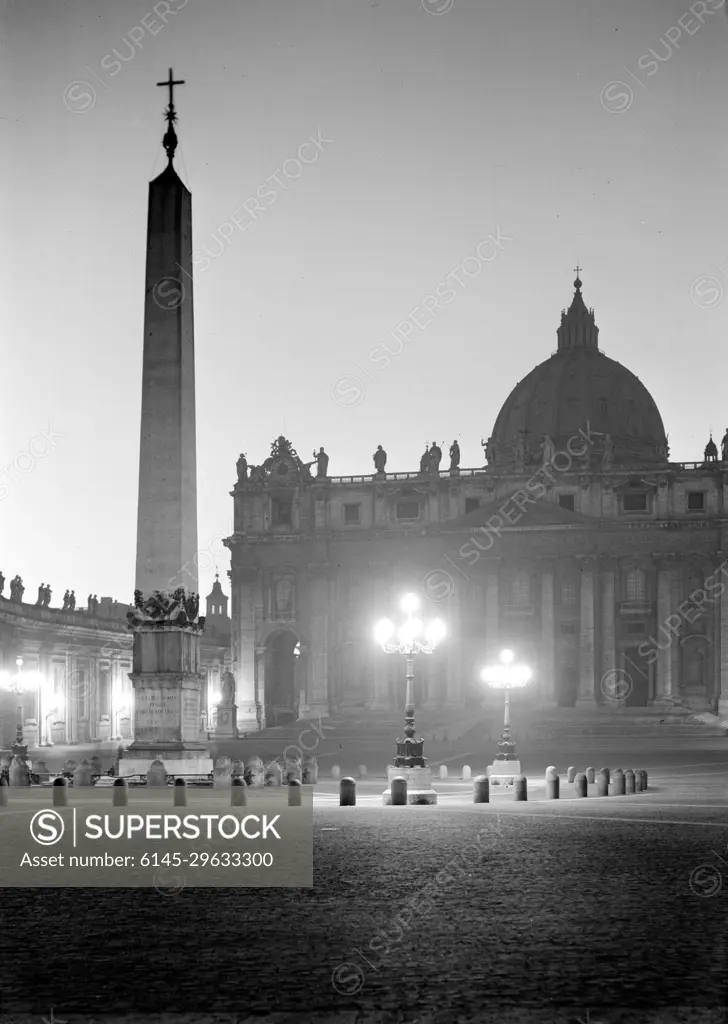 Poll photo collection. Rome: visit to the Vatican City. Sint-Pietersbasiliek in the twilight tunker with the Egyptian obelisk in front. December 1937. Italy, Rome, Sint-Pietersplein, Vatican City