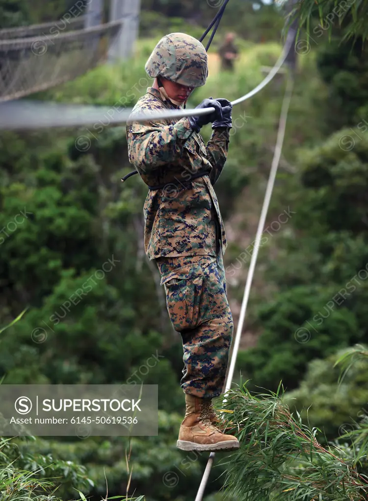 Lance Cpl. Hung Q. Nguyen crosses a two-strand rope bridge at the Jungle  Warfare Training Center at Camp Gonsalves July 7. Nguyen, along with his  unit, are participating in a seven-day training
