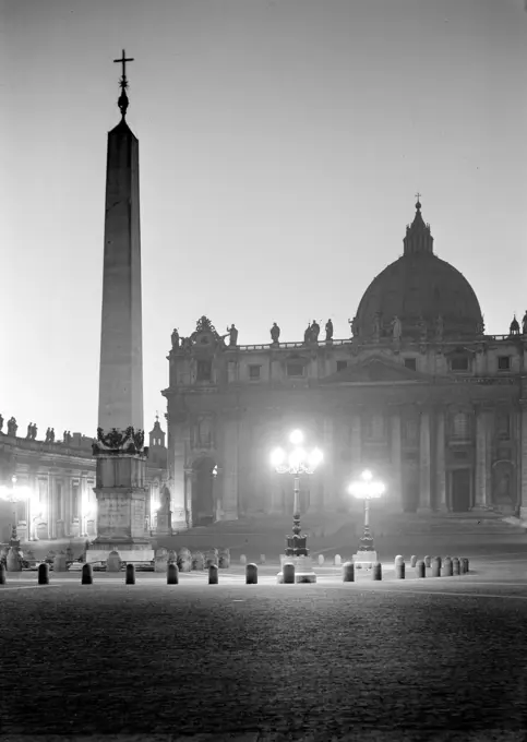 Poll photo collection. Rome: visit to the Vatican City. Sint-Pietersbasiliek in the twilight tunker with the Egyptian obelisk in front. December 1937. Italy, Rome, Sint-Pietersplein, Vatican City