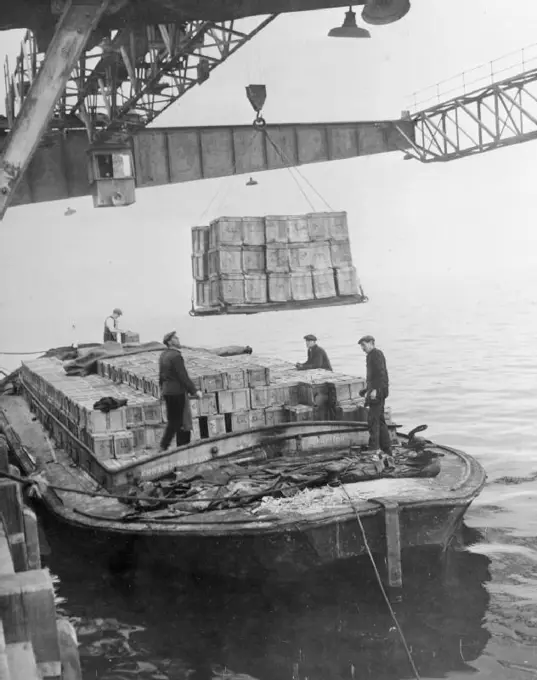 Invasion Build-up- Preparations For the D-day Landings, UK, 1944 At a port somewhere in Britain, boxes of rations are swung from the jetty into a barge in preparation for transportation to the Second Front.